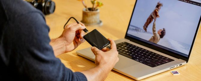 A man sitting at a table with a laptop and cell phone