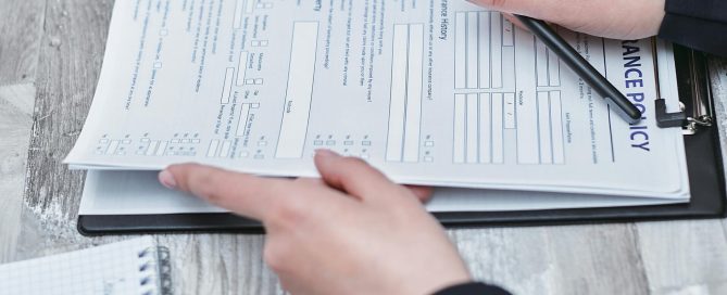 Free Close-up of hands analyzing insurance policy paperwork with pen on table. Stock Photo